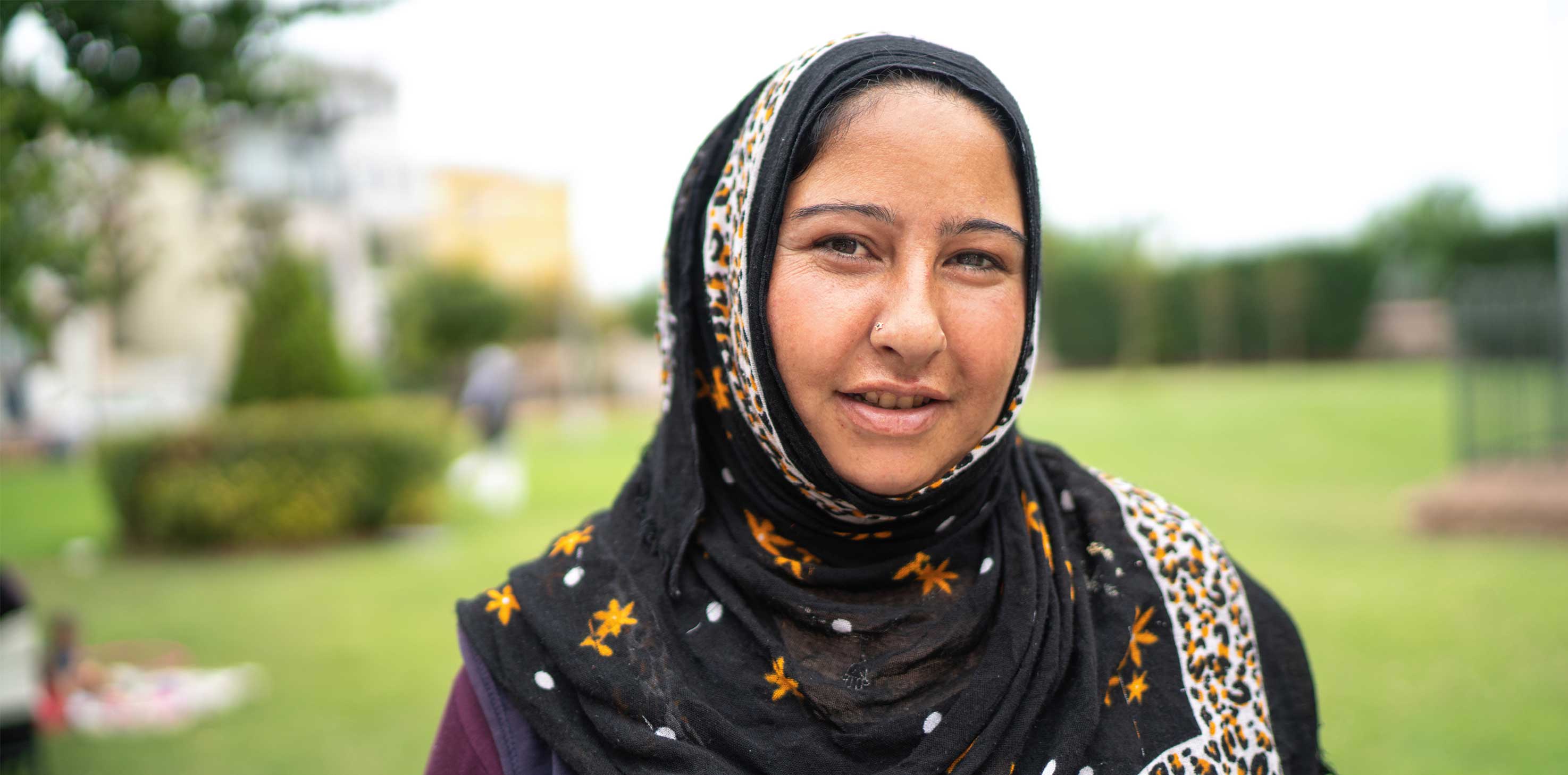 A headshot of a woman of South Asian descent wearing a hijab, smiling softly at the camera.