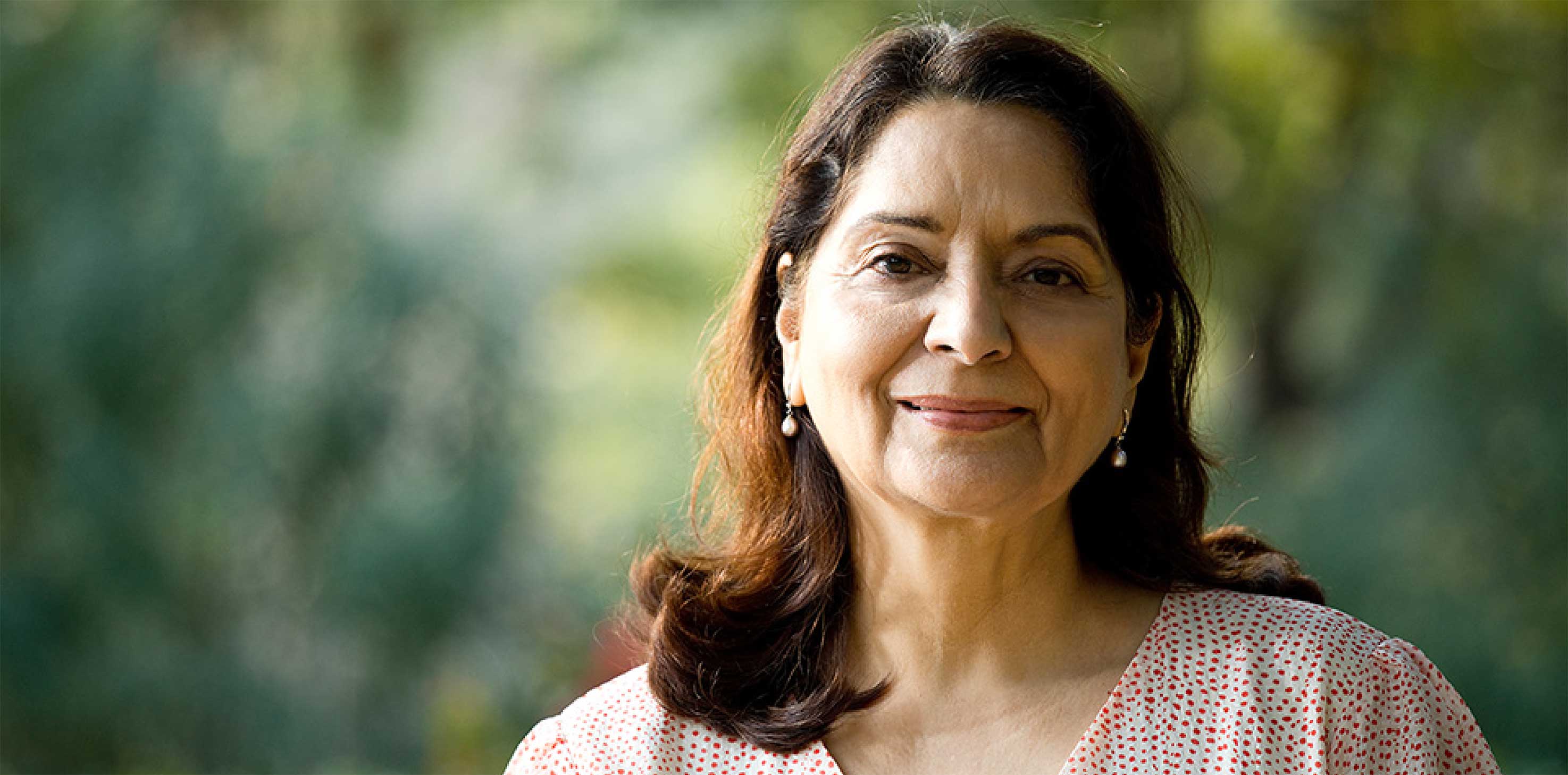 A headshot of a middle-aged woman of South Asian descent, smiling softly at the camera.